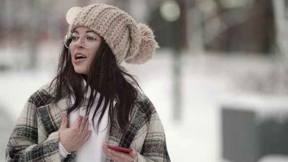 Funny Teen Girl Is Singing Song Outdoor at City at Winter Day Listening To Music By Smartphone