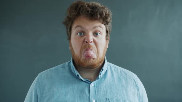 Portrait of Guy Showing Tongue with Hostile Face Then Putting on Glasses and Looking at Camera