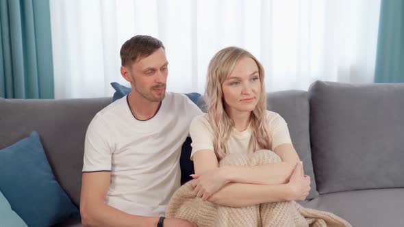 Unhappy Married Couple Sitting on the Couch After a Quarrel the Guy Asks the Girl for Forgiveness