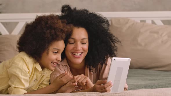 African American Woman and Litle Girl Talking on Video Call Using Digital Tablet