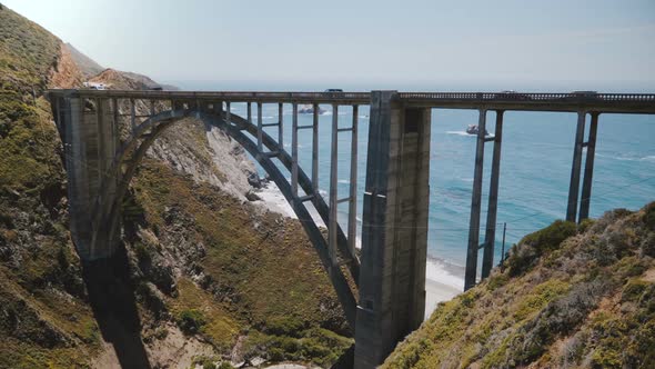 Epic Background Medium Shot of Iconic Bixby Canyon Bridge, Cars on Highway 1 and Pacific Ocean