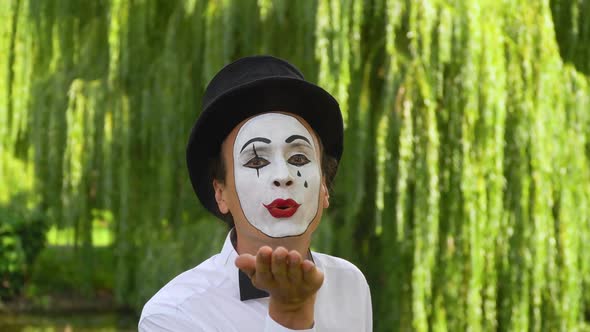 Mime on the Park Shows Pantomime. Mime in a Black Hat Blowing Kisses