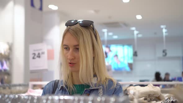 Beautiful woman chooses and buys clothes in shopping mall