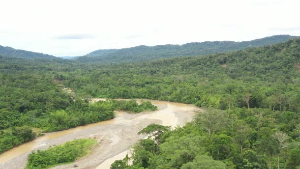 Drone shot following a large river inside a tropical forest at a high altitude