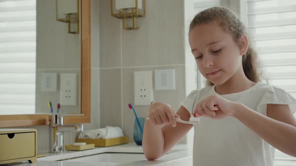 Portrait Happy Cute Young Teenage Girl Squeezing Toothpaste Onto Toothbrush in Her Bathroom