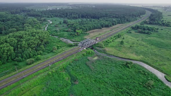 Railway Bridge Among Green Meadows Over a Small River in the Countryside