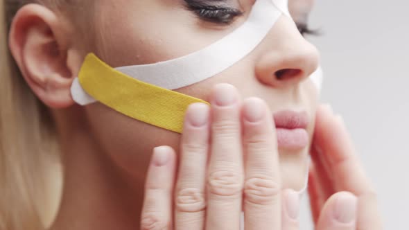 Therapist is applying kinesio tape to female face. Kinesiology and recovery treatment.