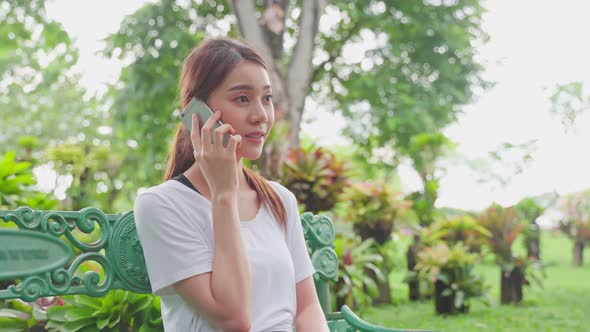 Asian woman enjoy communicate talking on mobile phone in public park after exercise.