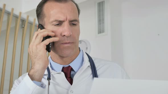 Doctor Talking on Phone with Patient Discussing Medical Report