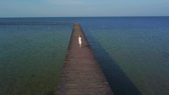 A Girl Walks on a Wooden Pier Near the Sea