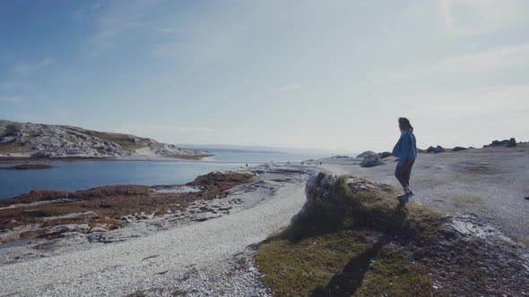 Woman on tranquil shore in sunlight