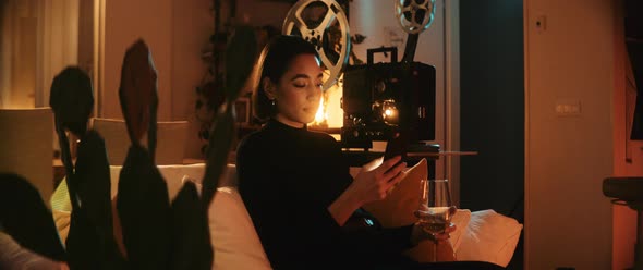 Young woman typing into her phone with bright light coming from the background