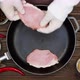 The cook puts the meat on the pan. Sliced pork steaks in a cast iron skillet. Black peppercorns - VideoHive Item for Sale