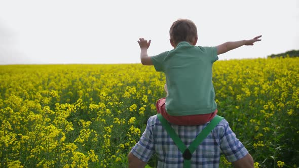 Farmer Carrying Grandson on Shoulders in Field