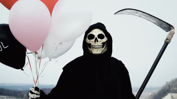 Death with a Scythe Holds Balloons and Hides Behind Them, but Then Shows a Creepy Face That Laughs