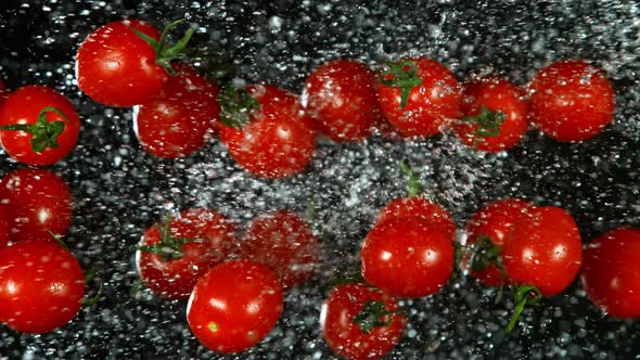 Super Slow Motion Shot of Flying Fresh Tomatoes and Water Side Splash on Black at 1000Fps.