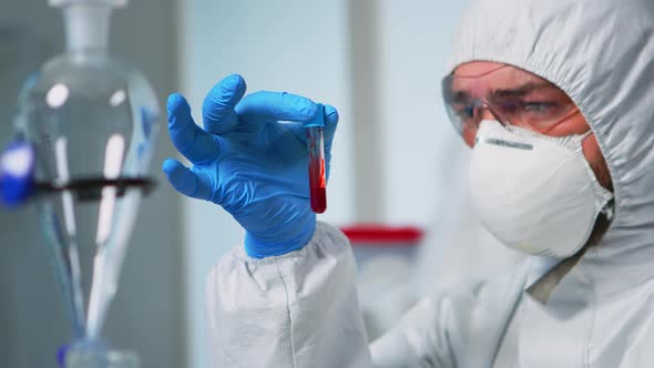 Scientist Holding Blood Sample Wearing Protection Suit