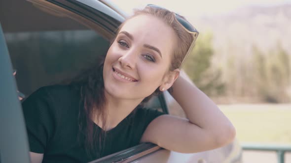 Attractive Girl with Light Makeup Leans Out of Automobile