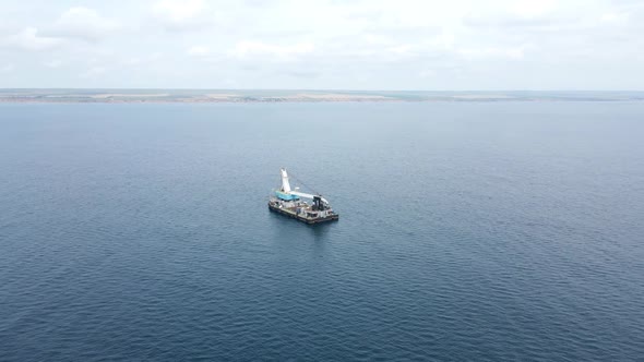 Cargo Ship with a Crane is at Sea Far From the Shore