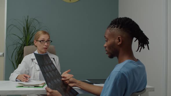 Male Patient Looking at MRI Image Questioning Female Doctor Indoors