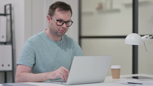 Thumbs Down By Young Man with Laptop at Work