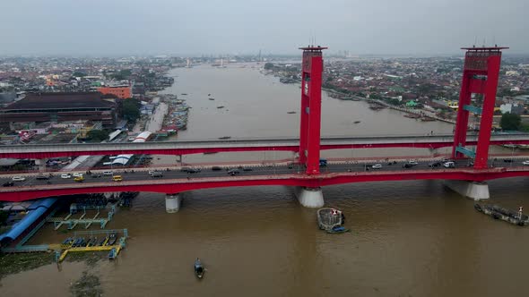 Foggy day over Palembang city with heavy traffic over Ampera bridge, aerial side fly view