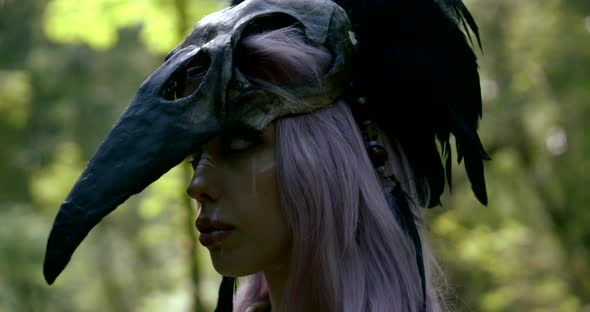 Young Woman with Plague Mask on Head Poses Against Forest