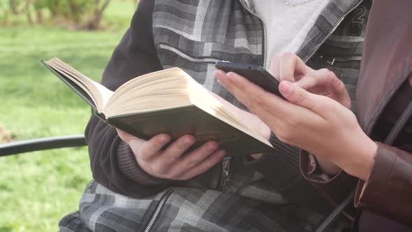 Couple Is Sitting On A Bench In The Park In The Spring And Reading An Interesting Book