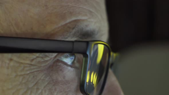 An Elderly Man with Glasses Looks at the Computer Screen