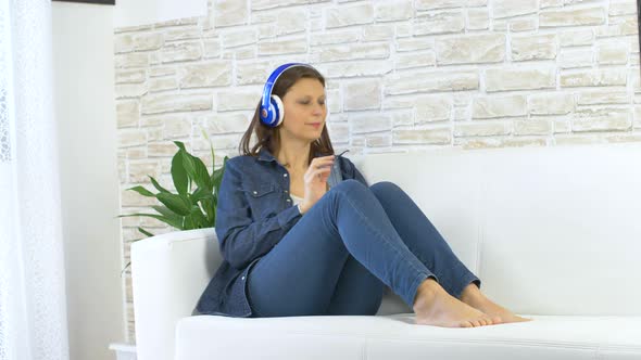 woman dressed in jeans dancing and listening music with headphones