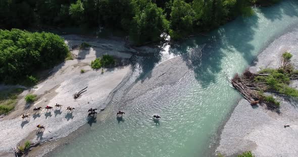 Equestrian Group Cross a Mountain River  Drone Shot