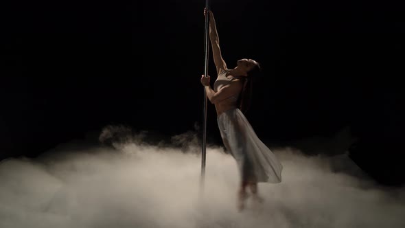 Woman with Sexy Shape Is Dancing Near the Pole. Black Smoke Background