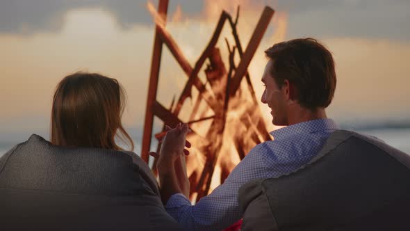 A Young Couple is Sitting on the Beach By the Fire