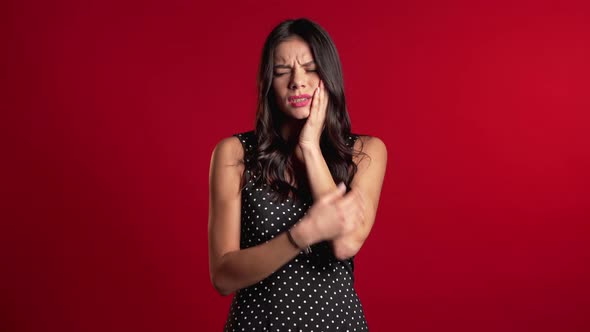 Young Pretty Hispanic Woman with Tooth Pain on Red Studio Background. Toothache