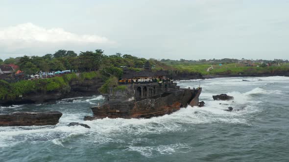 Strong Ocean Waves Crashing Into Rocky Cliff with Tanah Lot Temple in Bali Indonesia