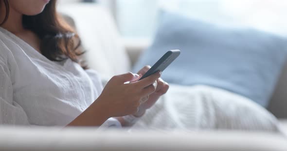 Woman use of smart phone and lying down on sofa