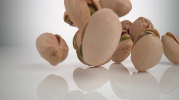 Camera follows pistachios falling on surface. Slow Motion.