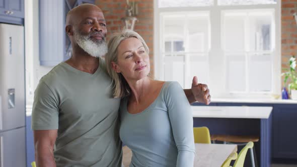 Mixed race senior couple hugging each other at home