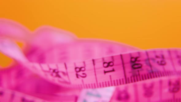 Close Up of a Pink and Yellow Measure Tape on Colored