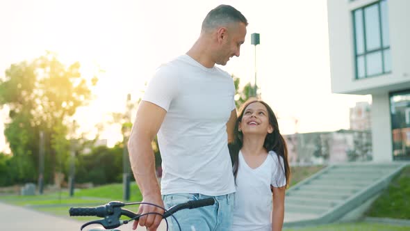 Dad and Daughter Walk Around Their Area After Cycling at Sunset