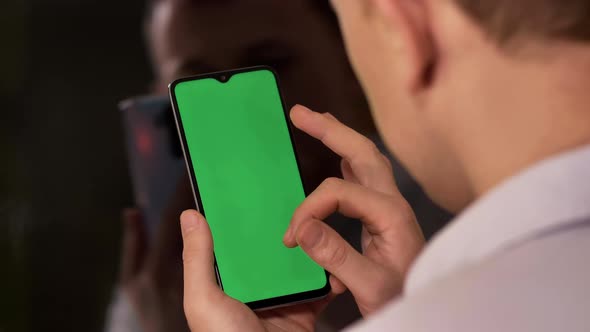 Young Man with a Phone Moves His Finger Across the Screen Chromakey Back View