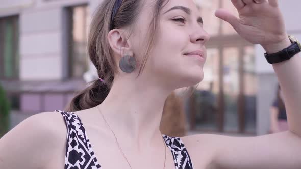 Close-up of Young Charming Caucasian Woman Looking Away Holding Hand at Forehead. Portrait of