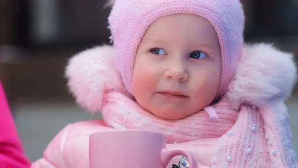 Funny Small Girl Smiles and Holds Pink Cup with Tea Closeup