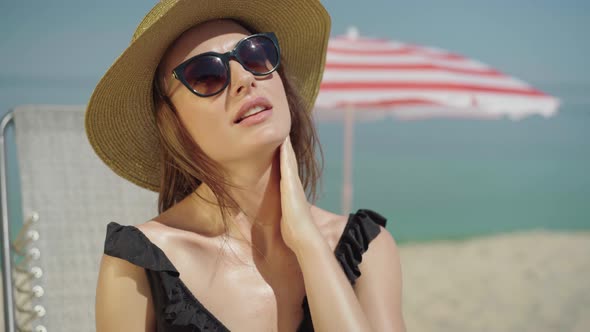 Portrait of Happy Relaxed Woman Rubbing Sunscreen on Chest. Young Beautiful Caucasian Lady Applying