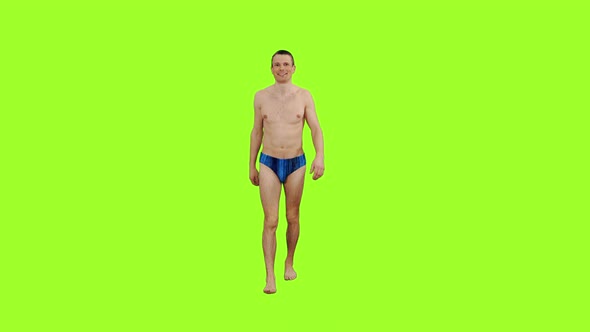 Handsome Young Male in Swim Trunks Walks on Green Background