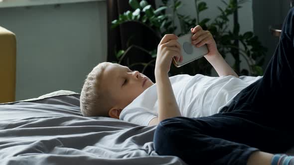 Portrait of A Child Boy Looking at the Phone Screen Playing a Game on a Smartphone