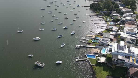 Aerial fly over suburban waterfront home, houses, neighborhood properties with boats, yacht, sailboa