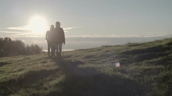 Young Friends Hiking Toward Camera in Mountain Outdoor Nature Scenery During Summer Sunrise or