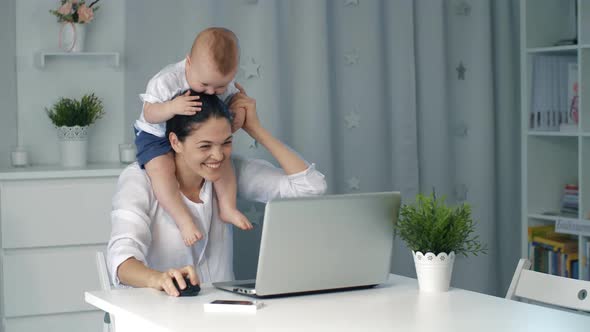 Mother with Baby Working on Laptop at Home