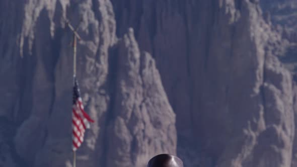 Cowboy against mountains and american flag standing proud